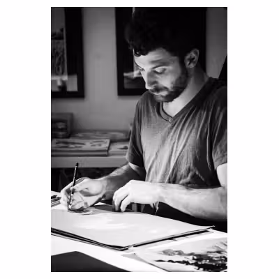 photo en noir et blanc d'Adrien Demont en train de dessiner
