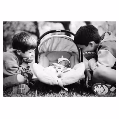 Deux jeunes enfants regardent un bébé dans couffin