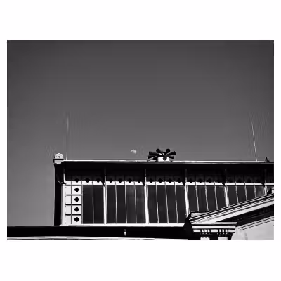 photographie du toit d'une halle avec la Lune en plein jour
