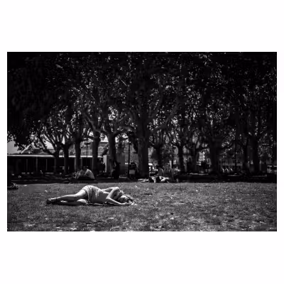 Photographie de rue sur les quais de Bordeaux. Une femme dort dans l'herbe.