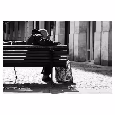 homme âgé en train de lire le journal sur un banc
