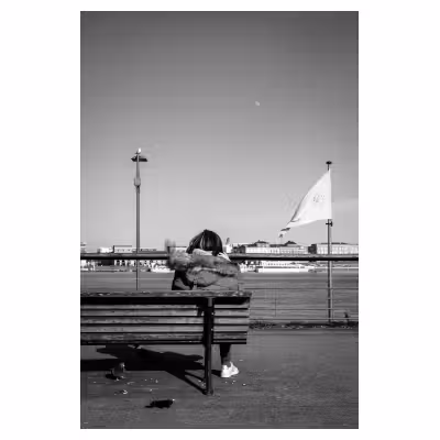 photo noir et blanc d'une personne assise sur un banc public