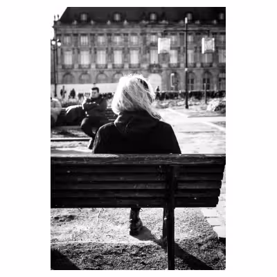 photo noir et blanc d'une personne assise sur un banc public