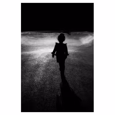 contre jour d'un enfant seul au centre d'une aire de jeu