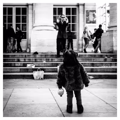 jeune enfant vue de dos en train de regarder un homme qui chante dans la rue