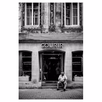 un homme corpulent est assis devant un magasin de vente de chaussures de sport