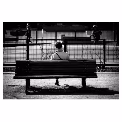 photographie de dos d'une personne assise sur un banc donnant l'impression de n'avoir qu'une jambe