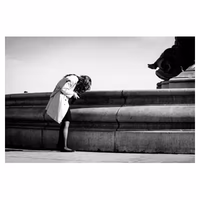 jeune femme courbée qui regarde l'écran de son appareil photo dans la rue devant une fontaine