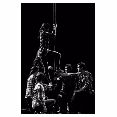 jeunes artistes de cirque tenant un poteau sur lequel monte une jeune femme