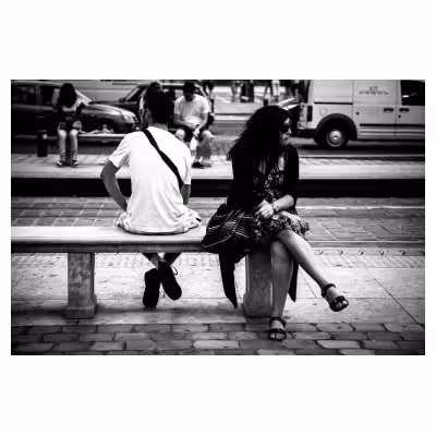 une femme et un homme assis dos à dos sur un banc