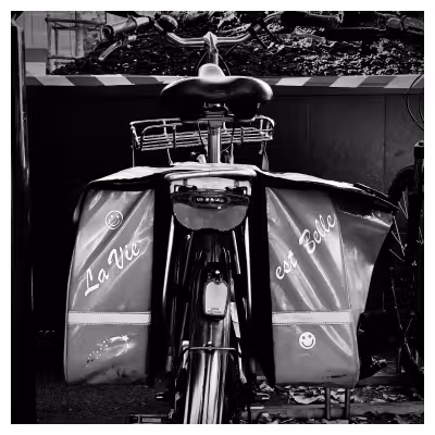 photographie en noir et blanc de l'arrière d'un vélo avec des sacoches où est écrit « la vie est belle »