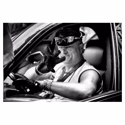 portrait d'un homme allemand au volant d'une voiture participant à un défilé de gayrpide qui fait un signe de la main