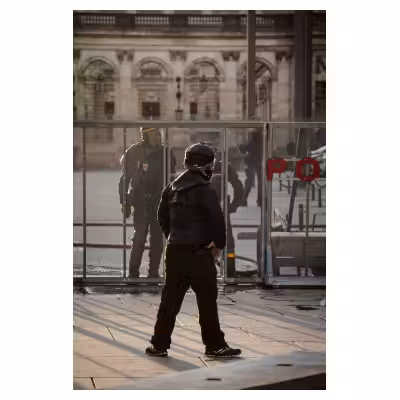 un manifestant casqué se tient debout en défiant des policiers
