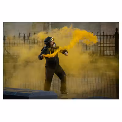un homme casqué est entouré d'un fumigène jaune