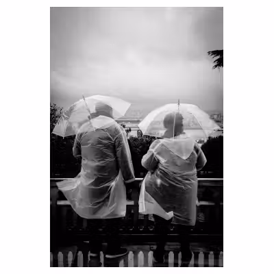 photo de deux touristes vus de dos revêtus chacun de ponchos transparents avec des parapluies