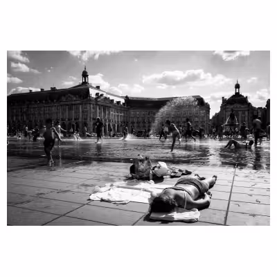 personne allongée en maillot de bain au bord d'un miroir d'eau en ville