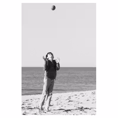 enfant jouant sur le sable en lançant un ballon en l'air
