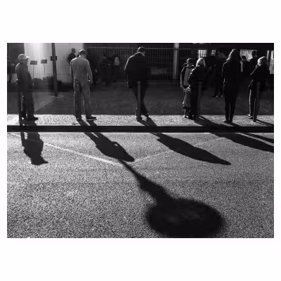 suite de personnes vues de dos appuyées sur des poteaux en bordure de trottoir
