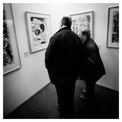 un homme et une femme vus de dos en train de regarder des tableaux exposés