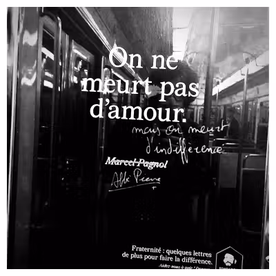 Photographie dans le metro d'une affiche de campagne de la Fondation Abbé Pierre où il est écrit « On ne meurt pas d'amour mais on meurt d'indifférence »