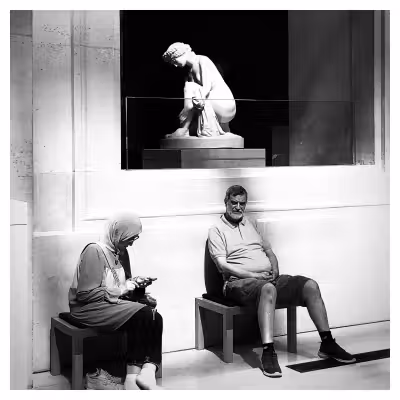photographie d'un couple assis au pied d'une statue au musée du Louvre