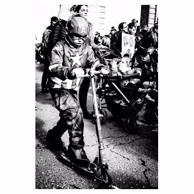 un enfant déguisé en Capitaine America sur une trottinette dans la rue