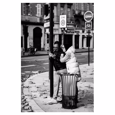 un couple souriant regarde un téléphone à l'angle d'une rue