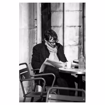 photographie d'un homme lisant le journal sur une terrasse