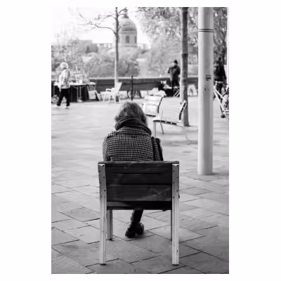 photographie noir et blanc d'une personne de dos sur un banc