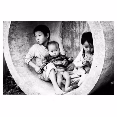 Trois enfants vietnamiens qui jouent dans un tube en béton