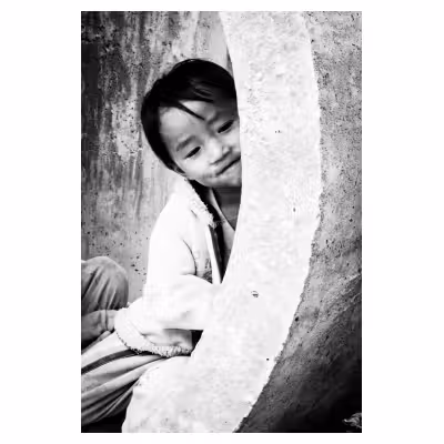 portrait d'un enfant vietnamien jouant dans un tube de béton