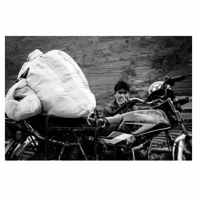 portrait d'un homme vietnamien assis derrière sa moto chargée de colis