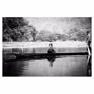 femme vietnamienne assise dans une longue barque sur l'eau
