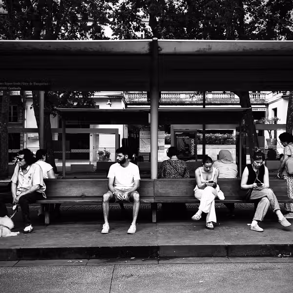 des personnes assises sur un banc qui restent sur leurs téléphones