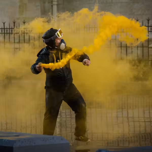 un homme casqué est entouré d'un fumigène jaune