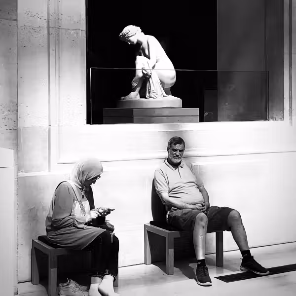 photographie d'un couple assis au pied d'une statue au musée du Louvre